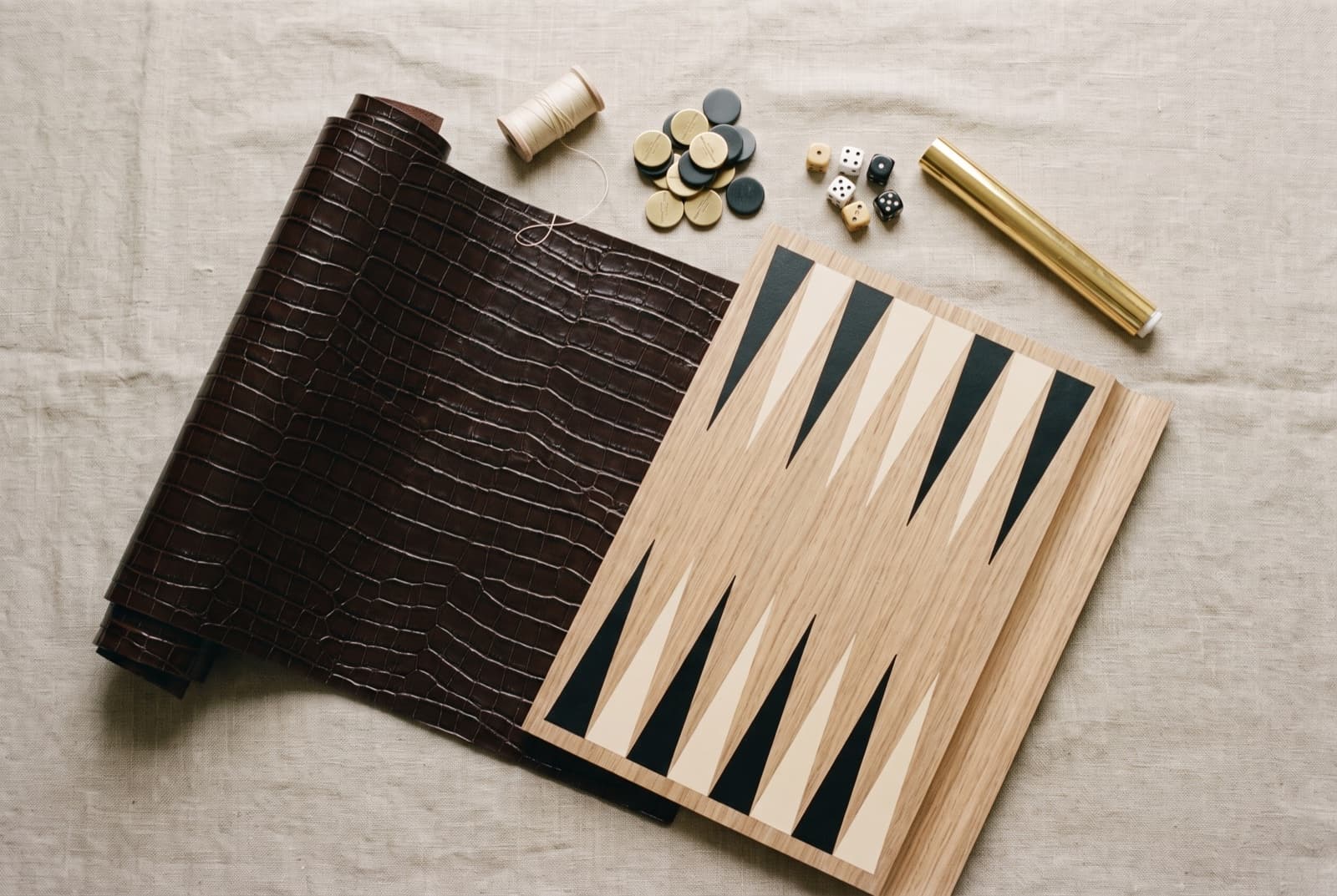 The raw materials — scaled leather, pale oak, brass, bone, gold foil